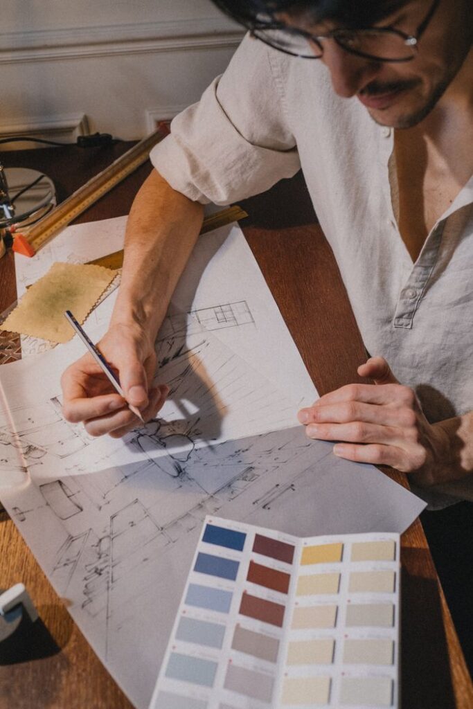 Creative adult sketching architectural designs with a color palette indoors.